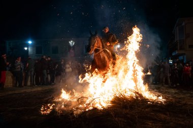 Atlı, atına binmiş, ateşin yanında. Fotoğraf 16 Ocak 2025 'te San Bartolome de Pinares, İspanya' da düzenlenen 