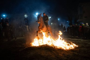 Atlı, atına binmiş, ateşin yanında. Fotoğraf 16 Ocak 2025 'te San Bartolome de Pinares, İspanya' da düzenlenen 