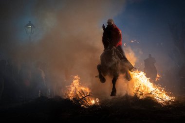 Atlı, atına binmiş, ateşin yanında. Fotoğraf 16 Ocak 2025 'te San Bartolome de Pinares, İspanya' da düzenlenen 