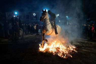 Atlı, atına binmiş, ateşin yanında. Fotoğraf 16 Ocak 2025 'te San Bartolome de Pinares, İspanya' da düzenlenen 