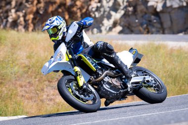 Motorcu güneşli bir günde yolda keskin bir viraj alıyor. Fotoğraf 12 Ağustos 2023 'te İspanya' nın Avila kentindeki Navalmoral de la Sierra kasabasında çekildi..