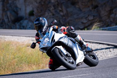 Motorcu güneşli bir günde yolda keskin bir viraj alıyor. Fotoğraf 12 Ağustos 2023 'te İspanya' nın Avila kentindeki Navalmoral de la Sierra kasabasında çekildi..