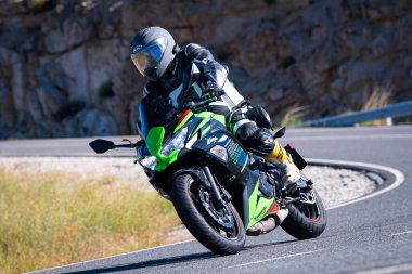 Motorcu güneşli bir günde yolda keskin bir viraj alıyor. Fotoğraf 12 Ağustos 2023 'te İspanya' nın Avila kentindeki Navalmoral de la Sierra kasabasında çekildi..
