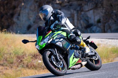 Motorcu güneşli bir günde yolda keskin bir viraj alıyor. Fotoğraf 12 Ağustos 2023 'te İspanya' nın Avila kentindeki Navalmoral de la Sierra kasabasında çekildi..