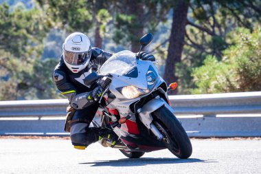 Motosikletinde oturan bir adam yolda oturmuş manzaranın ve güneşli günün tadını çıkarıyordu. Fotoğraf Mayıs 2024 'te Navaluenga kasabasında çekildi (Avila, İspanya).