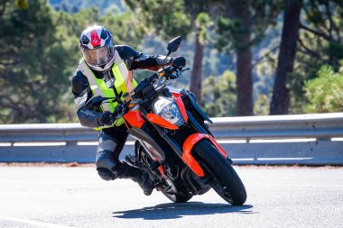 Motosikletinde oturan bir adam yolda oturmuş manzaranın ve güneşli günün tadını çıkarıyordu. Fotoğraf Mayıs 2024 'te Navaluenga kasabasında çekildi (Avila, İspanya).