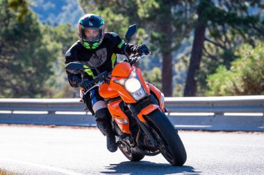 Motosikletinde oturan bir adam yolda oturmuş manzaranın ve güneşli günün tadını çıkarıyordu. Fotoğraf Mayıs 2024 'te Navaluenga kasabasında çekildi (Avila, İspanya).