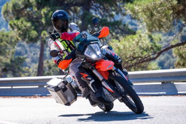 Motosikletinde oturan bir adam yolda oturmuş manzaranın ve güneşli günün tadını çıkarıyordu. Fotoğraf Mayıs 2024 'te Navaluenga kasabasında çekildi (Avila, İspanya).