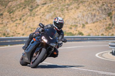 Güneşli bir günde 8 Ağustos 2020 tarihinde İspanya 'nın Avila ilinin Navalmoral de la Sierra limanında tehlikeli bir viraj alan motosikletçi
