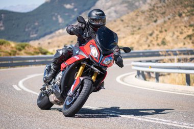 Güneşli bir günde 8 Ağustos 2020 tarihinde İspanya 'nın Avila ilinin Navalmoral de la Sierra limanında tehlikeli bir viraj alan motosikletçi