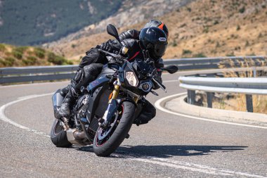 Motosikletli motorsikletli araca doğru keskin bir dönüş yapıyor.