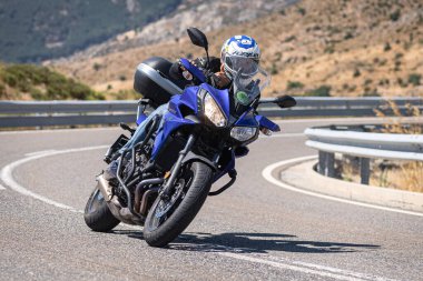 Motosikletli motorsikletli araca doğru keskin bir dönüş yapıyor.