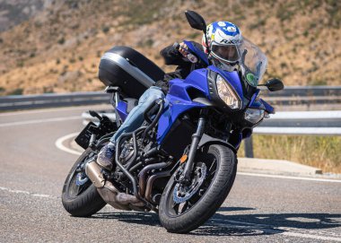 Motosikletli motorsikletli araca doğru keskin bir dönüş yapıyor.