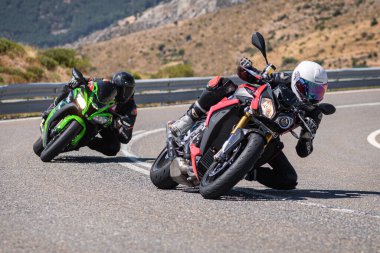 Motosikletli motorsikletli araca doğru keskin bir dönüş yapıyor.