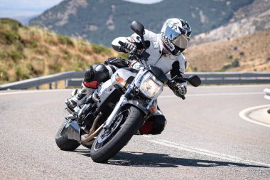 Motosikletli motorsikletli araca doğru keskin bir dönüş yapıyor.