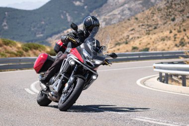 Motosikletli motorsikletli araca doğru keskin bir dönüş yapıyor.