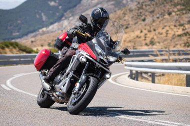 Motosikletli motorsikletli araca doğru keskin bir dönüş yapıyor.