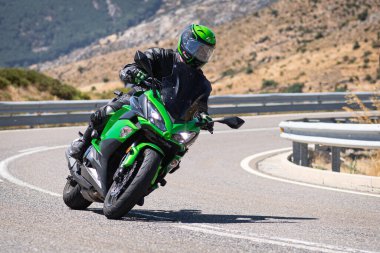 Motosikletli motorsikletli araca doğru keskin bir dönüş yapıyor.