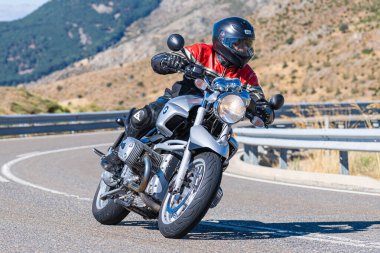 Motosikletli motorsikletli araca doğru keskin bir dönüş yapıyor.