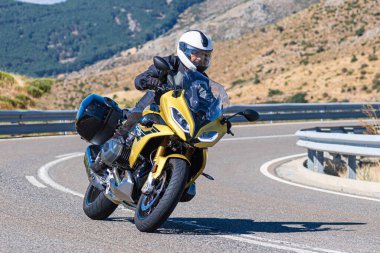 Motosikletli motorsikletli araca doğru keskin bir dönüş yapıyor.