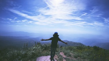 Asian man travel relax in the holiday. Stand and watch landscape on the Moutain. Mountain Park happily. In Thailand clipart