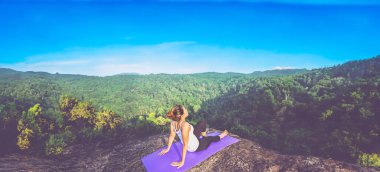 Asian women relax in the holiday. Play if yoga. On the Moutain rock cliff. Nature of mountain forests in Thailand clipart