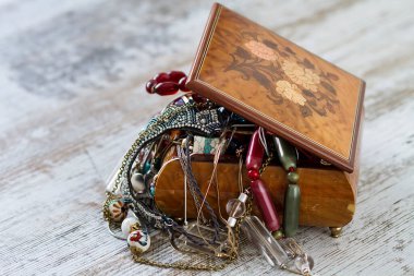 Kolye ve kostüm mücevherleriyle dolu antik ahşap bir mücevher kutusu.