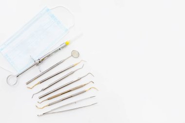 Diş muayenesi konsepti. Diş fırçası, diş fırçası ve yüz maskesi beyaz arka planda, düz yerde. Metin için yer.