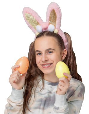 Mutlu Paskalyalar. Paskalya tavşanı kulakları ve renkli Paskalya yumurtaları olan sevimli bir kız. Uzayı kopyala Diş teli takmış gülümseyen kız..