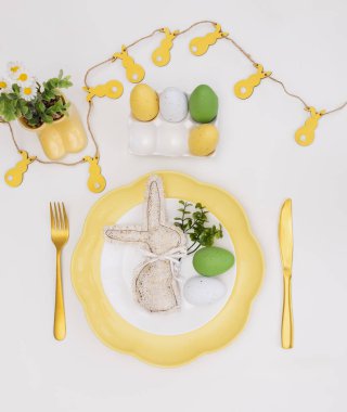 Mutlu Paskalyalar. Paskalya kutlaması. Dikey beyaz, sarı tabak, dekoratif tavşan, yumurta, izole beyaz arka plan. Boşluğu kopyala, metin için yer, pankart.