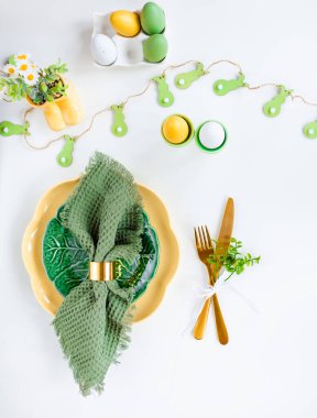 Mutlu Paskalyalar. Paskalya kutlaması. Üst manzara dikey peçete boş yeşil ve sarı plaka, paskalya yumurtaları, izole beyaz arka plan. Boşluğu kopyala, metin için yer, pankart.