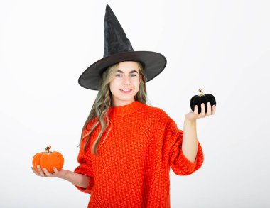 Cadılar Bayramı konsepti. Siyah şapkalı gülümseyen kızın portresi. Şeker yerine balkabağı Jack. Cadılar Bayramı dekoru. Beyaz arkaplanda izole