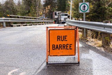 İnşaat işçileri arka planda çalışmakla meşgulken turuncu yol tabelasının köprüye erişimi engellemesi. Seçici odak