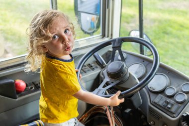 Otobüsün direksiyonunu tutan ve şoför gibi davranan şaşkın suratlı genç bir çocuk. Seçici odak