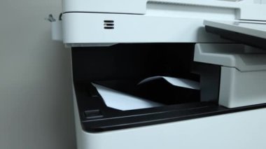 Yazıcı, modern teknolojiyi iş başında gösteren bir ofis ortamında yavaşça kağıt üretiyor. Seçici odak