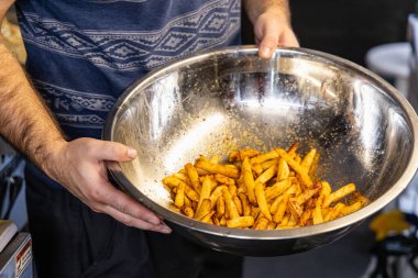 Şefin elinde büyük paslanmaz çelik bir kase taze pişmiş patates kızartması var. Seçici odak