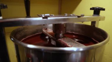 Endüstriyel çikolata makinesi fabrika ortamında eritilmiş çikolatayı karıştırarak üretim sürecini ve ekipmanlarını gözler önüne seriyor. Seçici odak