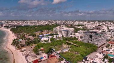 Havadan bakıldığında Meksika 'da bir tropikal şehir, güneşli bir gökyüzü altında sahil otelleri ve tatil beldeleri sergileniyor.