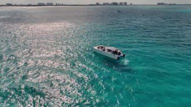 Turistlerle dolu motorlu tekne, parlak, güneşli bir gökyüzünün altında büyüleyici turkuaz Karayip denizinde bir uyanış yarattı.