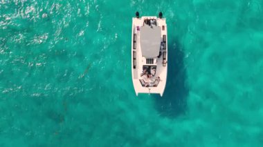 Turist ve mürettebatlı katamaran Meksika 'da turkuaz suda yavaş çekimde seyrediyor.
