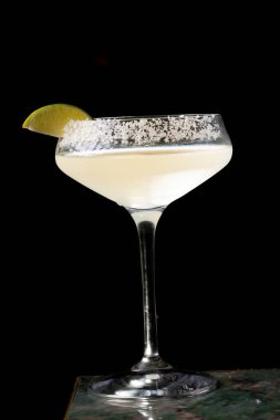 Limonlu bir bardak margarita kokteyli ve siyah bir arka plan.