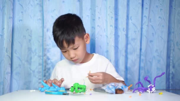 Koncentrovaný Asijský Chlapec Sedět Dělat Panenky Plasticinu Bílém Stole Domě — Stock video