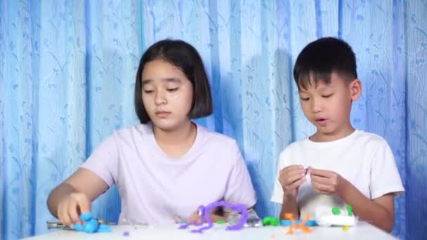 아이들 장난감을 가지고 아시아 소녀와 소년들이 앉아서 테이블 위에서 플라스틱으로 — 비디오