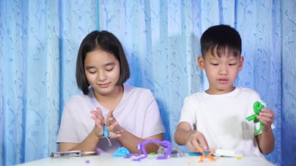 아이들 장난감을 가지고 아시아 소녀와 소년들이 앉아서 테이블 위에서 플라스틱으로 — 비디오