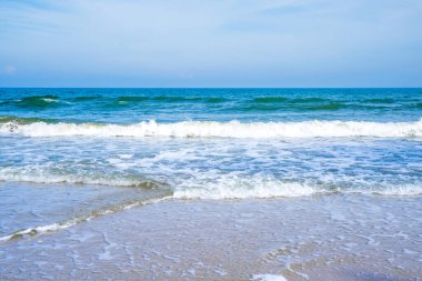 Açık mavi deniz dalgaları temiz kumsalda.