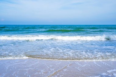 Açık mavi deniz dalgaları temiz kumsalda.