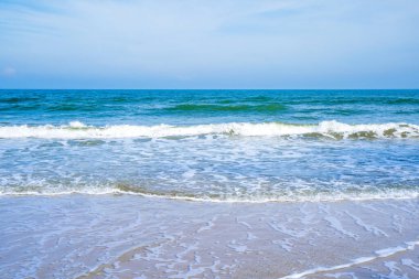 Açık mavi deniz dalgaları temiz kumsalda.