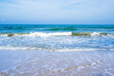 Açık mavi deniz dalgaları temiz kumsalda.