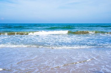 Açık mavi deniz dalgaları temiz kumsalda.