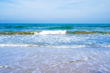 Açık mavi deniz dalgaları temiz kumsalda.